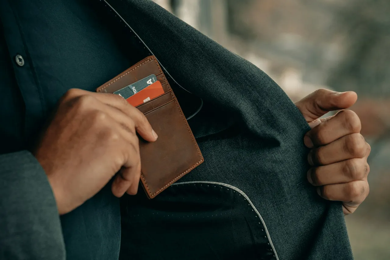 Mão guardando carteira com cartões no bolso do paletó